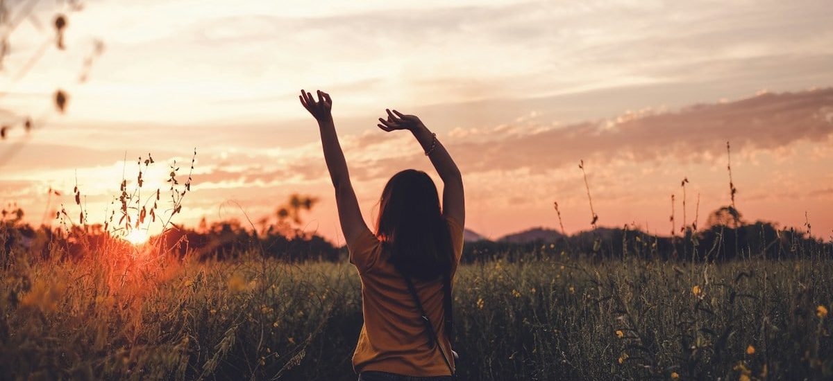 woman waving her hands during golden hour