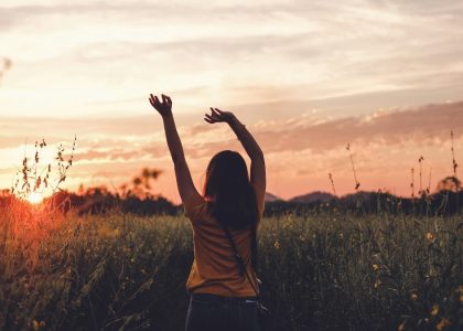 woman waving her hands during golden hour