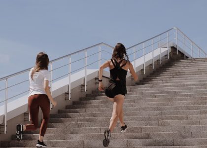 Two women running up stairs outdoors, embodying fitness and wellness.